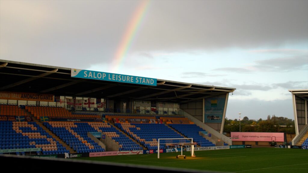 Image shows rainbow over one of the stands at the Montgomery Waters Meadow football stadium in Shrewsbury