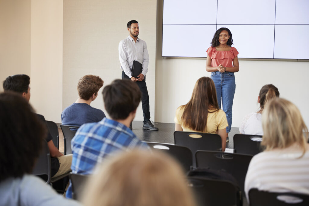 Student Giving Presentation To High School Class In Front Of Screen